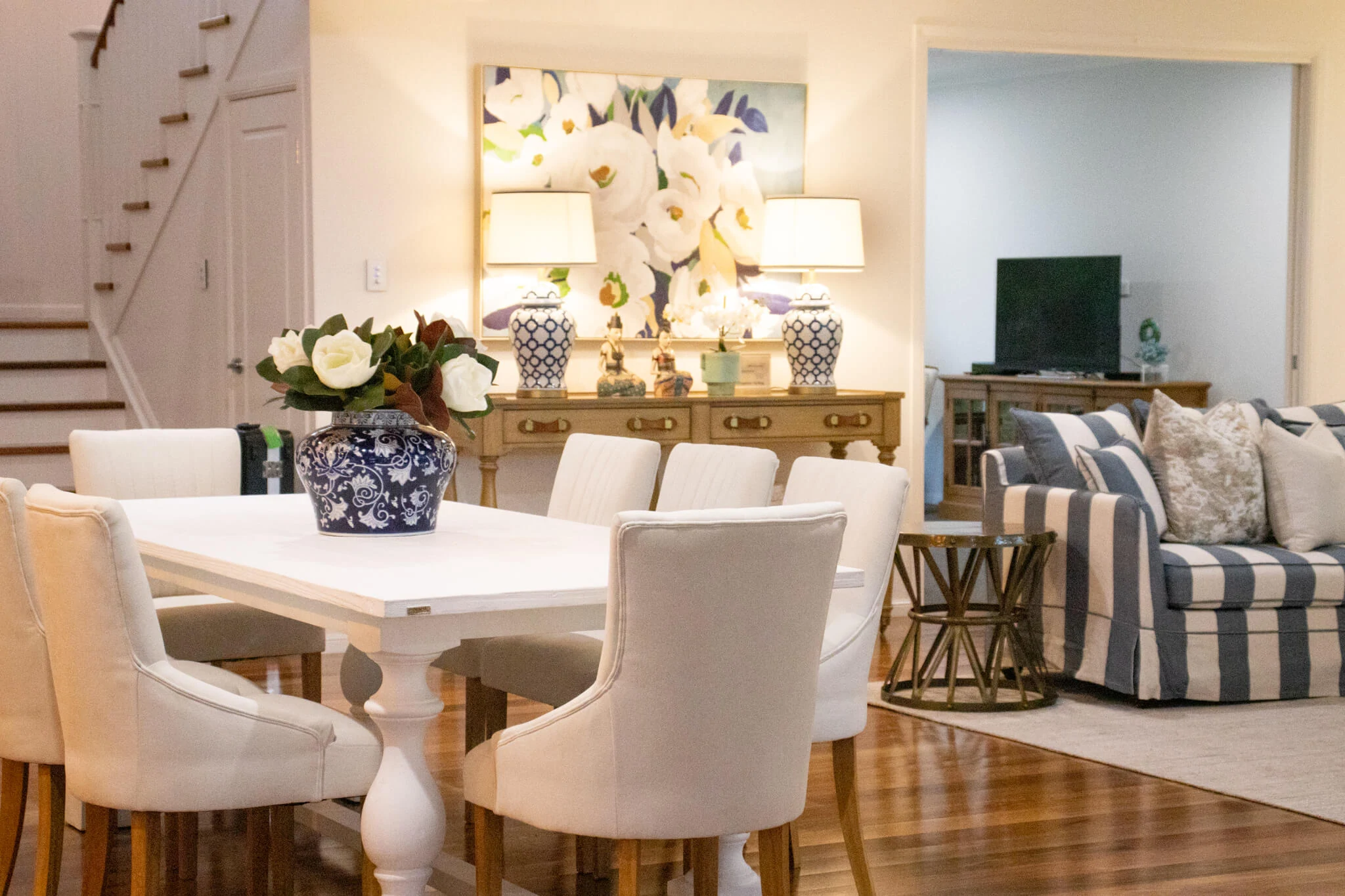 open-plan dining and living area with a blue striped soda and white dining table