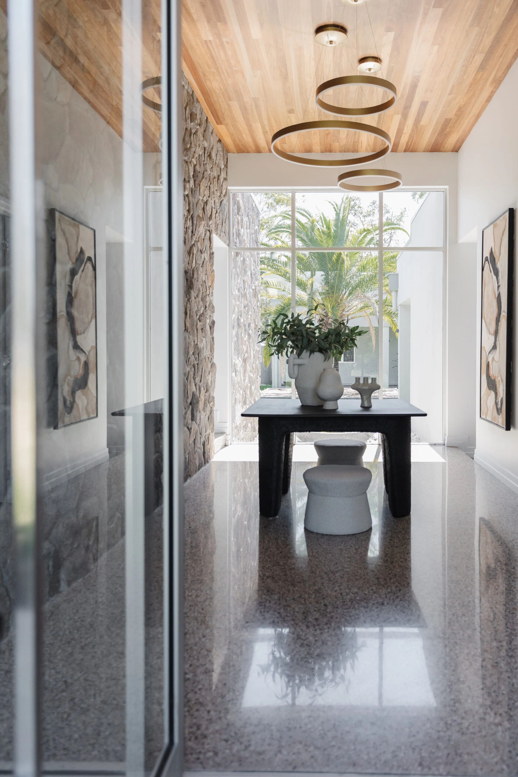 Modern dining room with wood ceiling, unique lighting, stone wall and styled with pot plants on the table