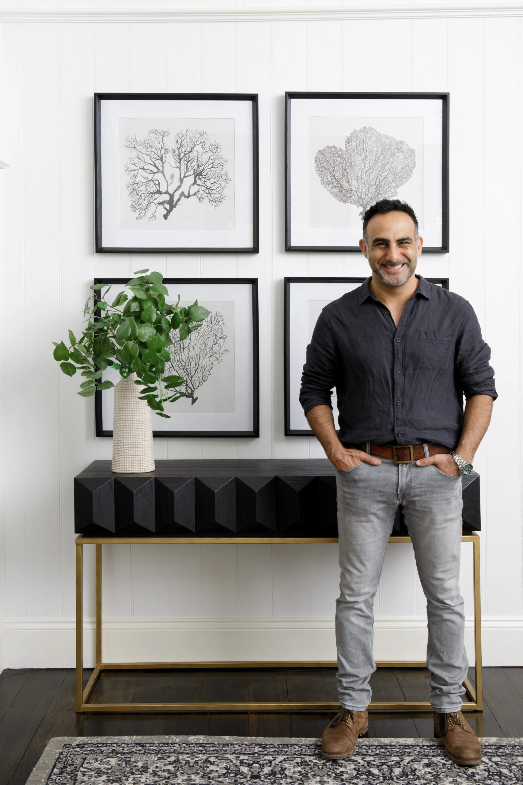 A man standing in a modern home in front of a side unit and wall art