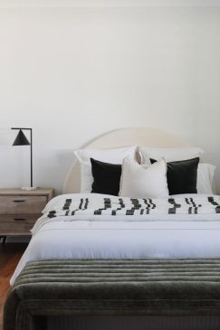 Modern bedroom styled with white sheets and green accents