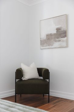 Comfortable seating in the corner of a white room, styled with abstract art and complimentary cushion