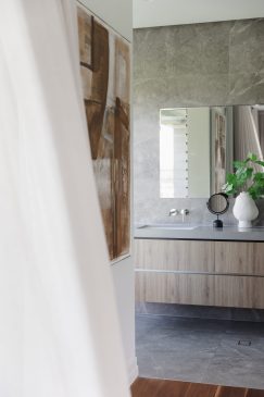 A view into a bathroom with large stone tiles and wooden vanity unit