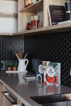 Modern kitchen with black hexagon backsplash tiles and styled with cook books.